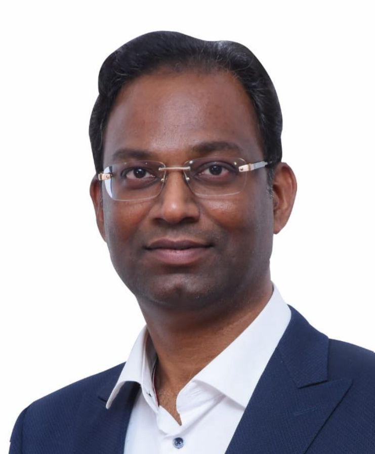 A man smiling and holding his hand to his forehead.